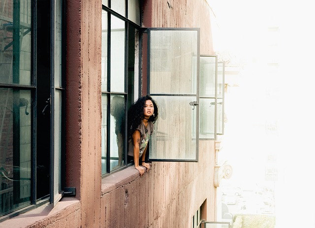 Činžiak, mladá žena pozerá z otvoreného okna.jpg